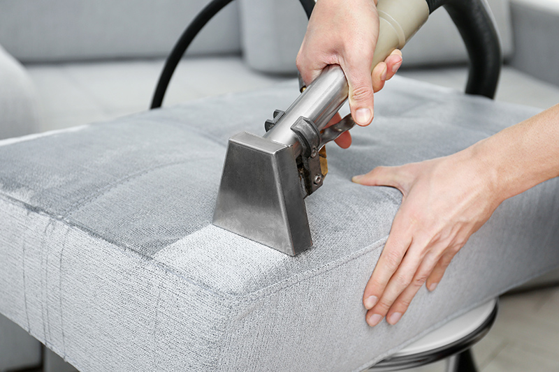 Dry cleaner's employee removing dirt from furniture in flat, closeup